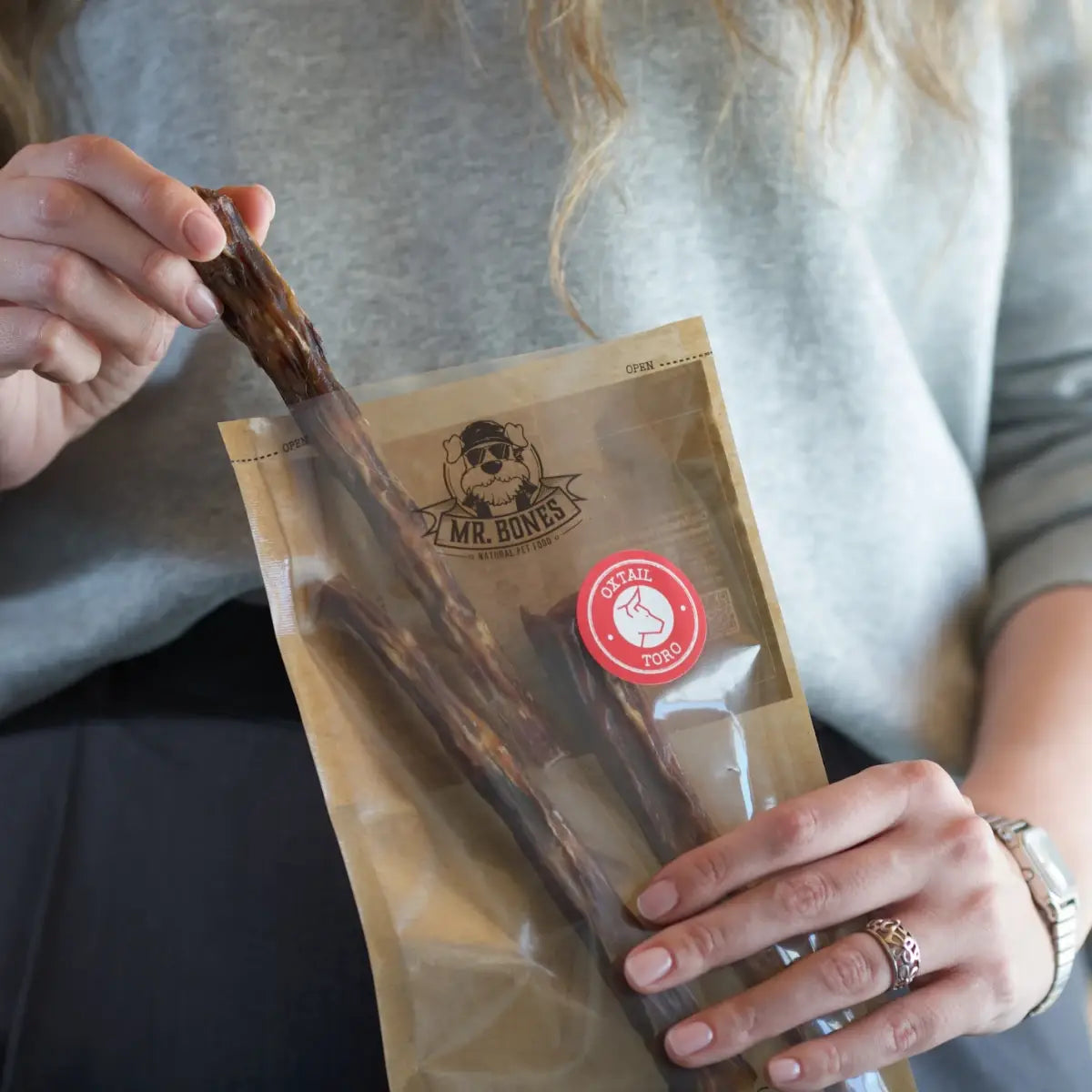 Three air-dried oxtail dog chews on a neutral background, natural dental treat for medium and large dogs.