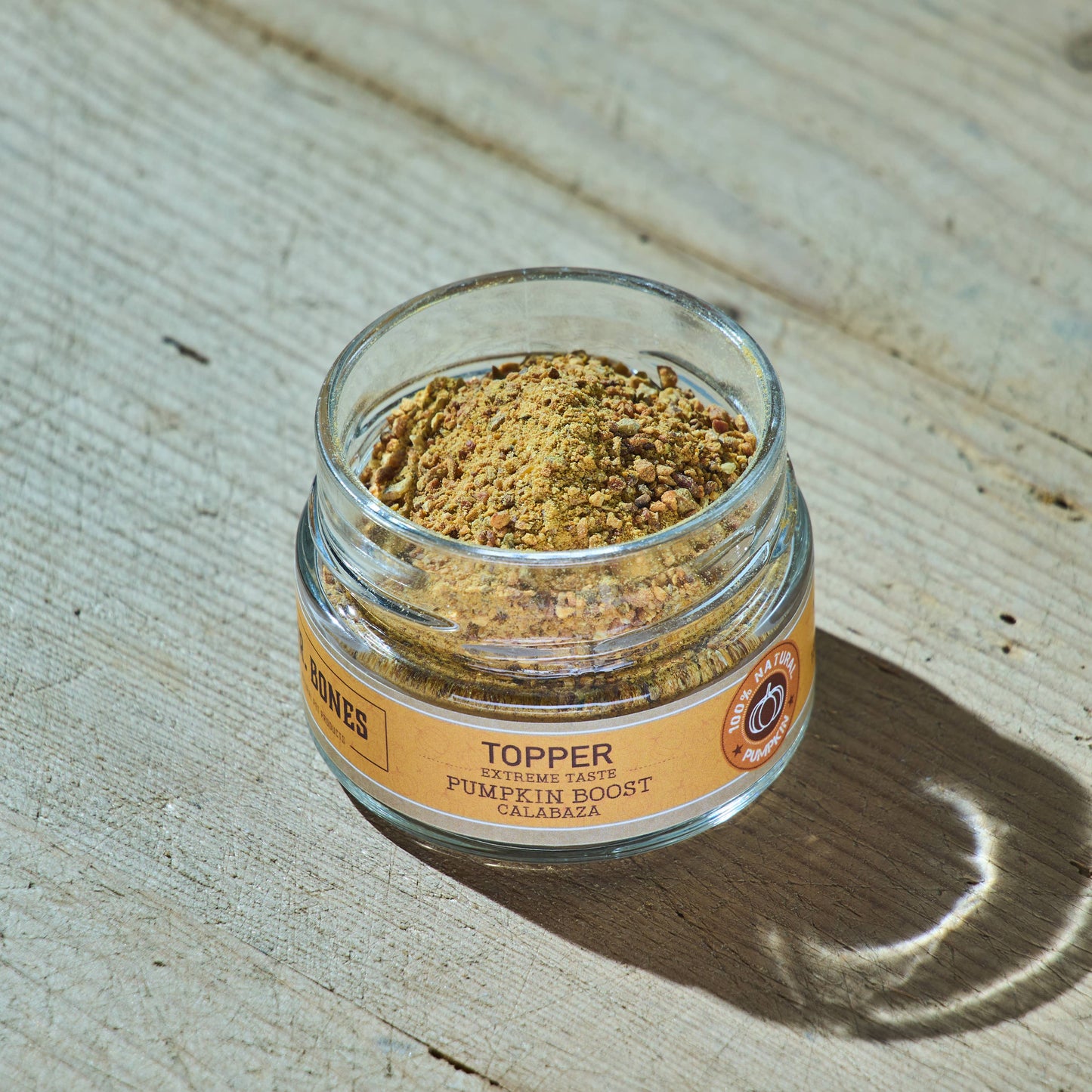 Glass jar of natural dehydrated pumpkin topper for dogs and cats with a wooden spoon, digestive health supplement.
