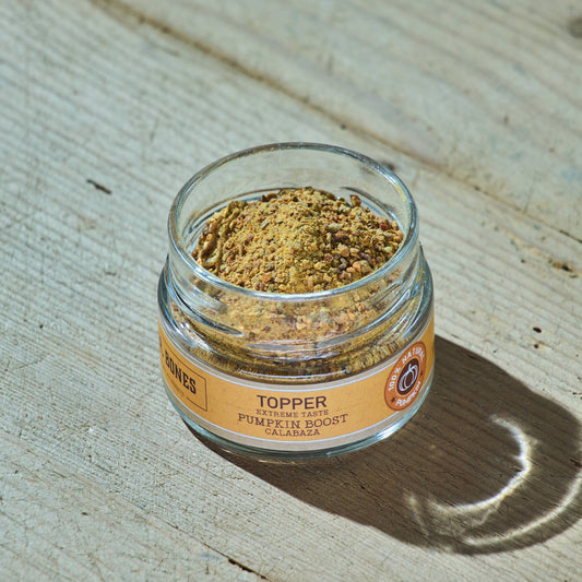 Glass jar of natural dehydrated pumpkin topper for dogs and cats with a wooden spoon, digestive health supplement.

